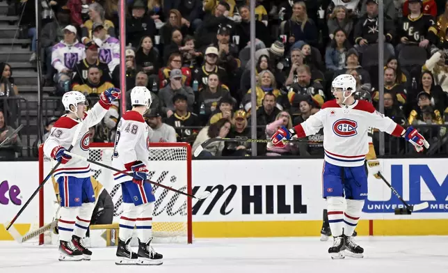 Montreal Canadiens right wing Cole Caufield (13), defenseman Lane Hutson (48) and left wing Juraj Slafkovsky celebrate after Caufield's goal against the Vegas Golden Knights during the second period of an NHL hockey game Tuesday, Dec. 31, 2024, in Las Vegas. (AP Photo/David Becker)