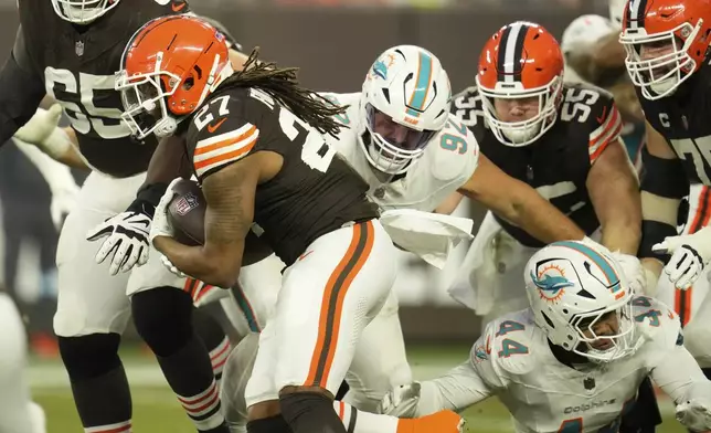 Cleveland Browns running back D'Onta Foreman (27) runs as Miami Dolphins defensive tackle Zach Sieler (92) and linebacker Chop Robinson (44) defend and during the first half of an NFL football game Sunday, Dec. 29, 2024, in Cleveland. (AP Photo/Sue Ogrocki)