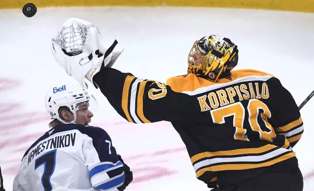 Boston Bruins goaltender Joonas Korpisalo (70) reaches to grab the puck over Winnipeg Jets center Vladislav Namestnikov (7) during the second period of an NHL hockey game, Thursday, Jan. 30, 2025, in Boston. (AP Photo/Charles Krupa)