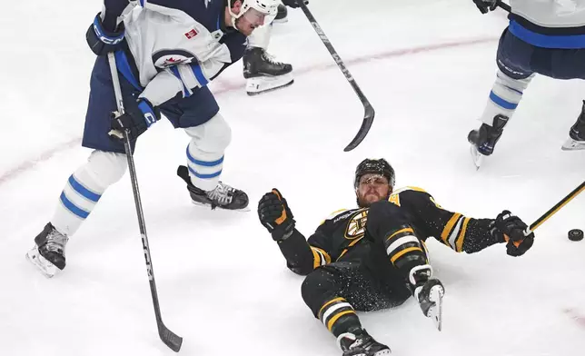 Boston Bruins right wing David Pastrnak, bottom right, is dropped to the ice by Winnipeg Jets defenseman Dylan Samberg (54) during the first period of an NHL hockey game, Thursday, Jan. 30, 2025, in Boston. (AP Photo/Charles Krupa)