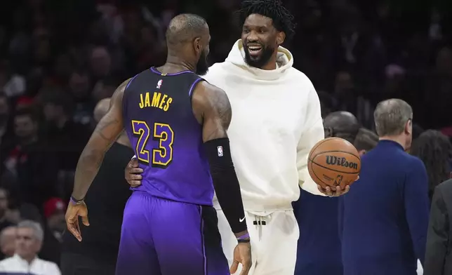 Philadelphia 76ers' Joel Embiid, right, and Los Angeles Lakers' LeBron James talk during the first half of an NBA basketball game, Tuesday, Jan. 28, 2025, in Philadelphia. (AP Photo/Matt Slocum)