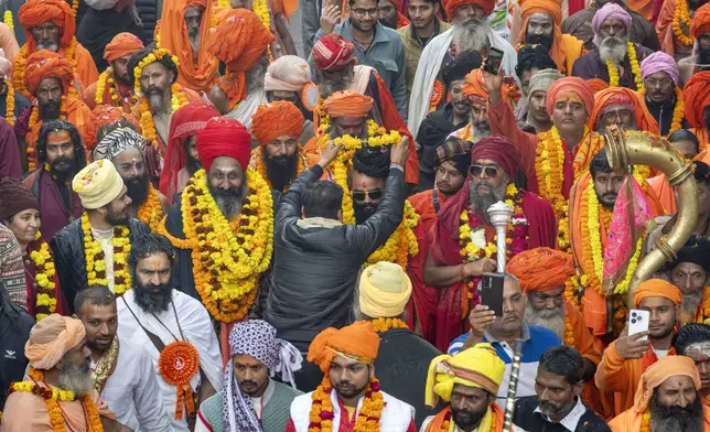 A devotee garlands a senior Hindu holy man walking in a procession, a day before the 45-day-long Maha Kumbh festival, in Prayagraj, India, Sunday, Jan. 12, 2025. (AP Photo/Ashwini Bhatia)