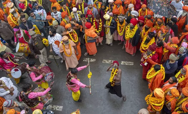 An ascetic dances with another as Hindu holy man walk in a procession, a day before the 45-day-long Maha Kumbh festival, in Prayagraj, India, Sunday, Jan. 12, 2025. (AP Photo/Ashwini Bhatia)
