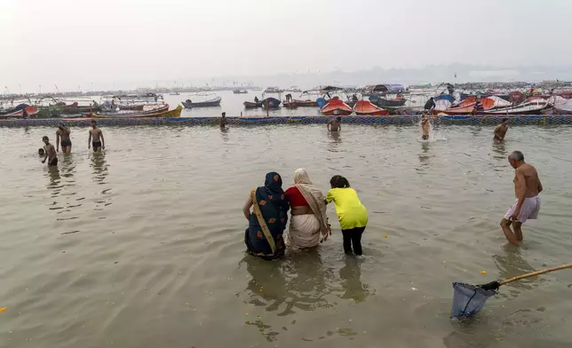 A family enters the water to take a dip at the confluence of the Ganges, the Yamuna and the mythical Saraswati rivers, a day before the official beginning of the 45-day-long Maha Kumbh festival, in Prayagraj, India, Sunday, Jan. 12, 2025. (AP Photo/Ashwini Bhatia)