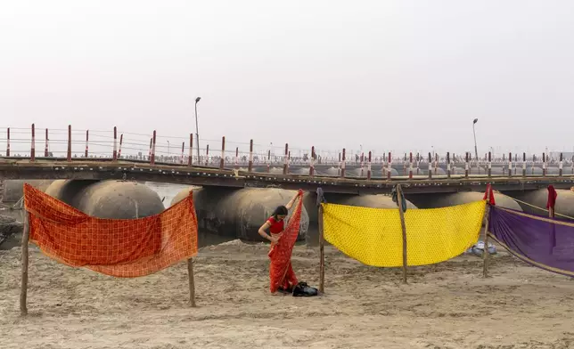 A Hindu woman devotee adjusts her saree as she changes after taking bath at the confluence of the Ganges, the Yamuna and the mythical Saraswati rivers, a day before the official beginning of the 45-day-long Maha Kumbh festival, in Prayagraj, India, Sunday, Jan. 12, 2025. (AP Photo/Ashwini Bhatia)