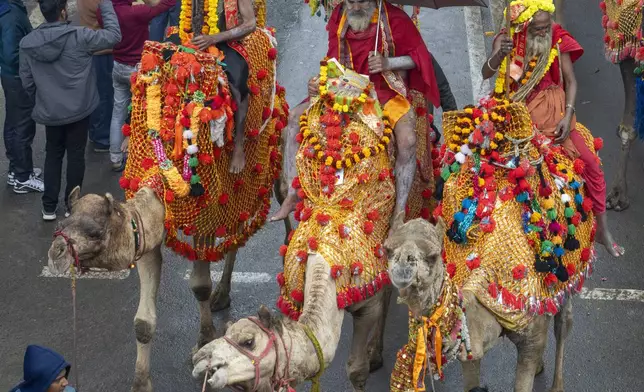 Hindu holy men ride camels during a procession, a day before the 45-day-long Maha Kumbh festival, in Prayagraj, India, Sunday, Jan. 12, 2025. (AP Photo/Ashwini Bhatia)