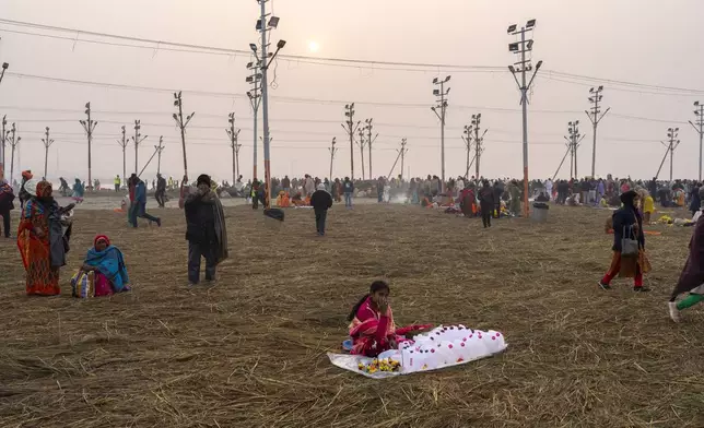 A woman sells empty plastic containers as devotees arrive to bathe at the confluence of the Ganges, the Yamuna and the mythical Saraswati rivers, a day before the official beginning of the 45-day-long Maha Kumbh festival, in Prayagraj, India, Sunday, Jan. 12, 2025. (AP Photo/Ashwini Bhatia)