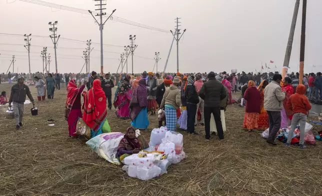 A woman sells empty plastic containers as devotees arrive to bathe at the confluence of the Ganges, the Yamuna and the mythical Saraswati rivers, a day before the official beginning of the 45-day-long Maha Kumbh festival, in Prayagraj, India, Sunday, Jan. 12, 2025. (AP Photo/Ashwini Bhatia)