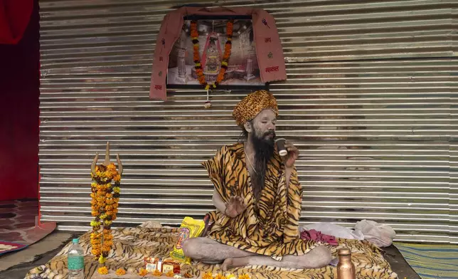 A Hindu holy man sips tea at his makeshift living quarters at the confluence of the Ganges, the Yamuna and the mythical Saraswati rivers, a day before the official beginning of the 45-day-long Maha Kumbh festival, in Prayagraj, India, Sunday, Jan. 12, 2025. (AP Photo/Ashwini Bhatia)