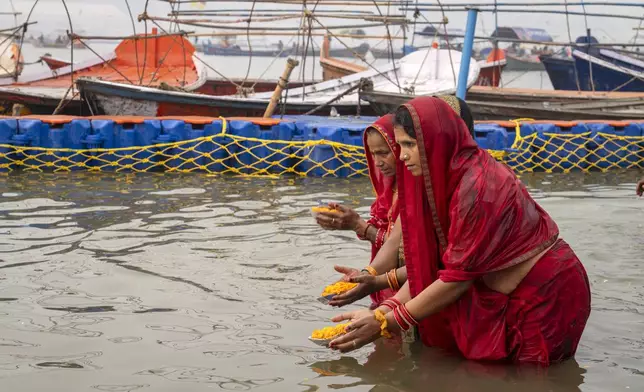 Hindu women devotees pray after taking bath at the confluence of the Ganges, the Yamuna and the mythical Saraswati rivers, a day before the official beginning of the 45-day-long Maha Kumbh festival, in Prayagraj, India, Sunday, Jan. 12, 2025. (AP Photo/Ashwini Bhatia)