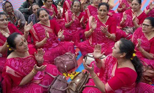 Hindu women devotees sing hymns as they gather at the confluence of the Ganges, the Yamuna and the mythical Saraswati rivers, a day before the official beginning of the 45-day-long Maha Kumbh festival, in Prayagraj, India, Sunday, Jan. 12, 2025. (AP Photo/Ashwini Bhatia)