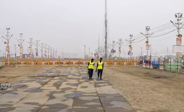 Sanitation workers walk after cleaning an area on the banks of the Ganges river, where the 45-day-long Maha Kumbh festival will officially begin on Monday, in Prayagraj, India, Sunday, Jan. 12, 2025. (AP Photo/Ashwini Bhatia)