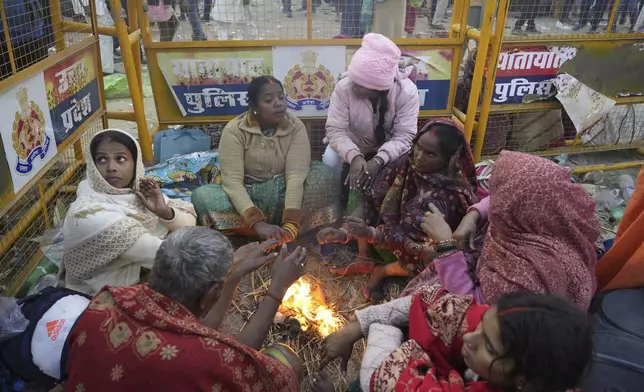 Hindu devotees keep warm by a bonfire on the banks of the Sangam, the confluence of the Ganges, the Yamuna and the mythical Saraswati rivers, on "Mauni Amavasya" or new moon day during the Maha Kumbh festival in Prayagraj, Uttar Pradesh, India, Wednesday, Jan. 29, 2025. (AP Photo/Deepak Sharma)