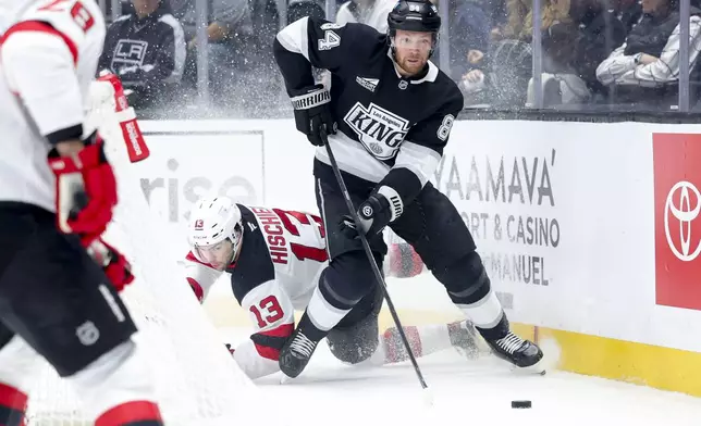 Los Angeles Kings defenseman Vladislav Gavrikov, right, moves the puck ahead of New Jersey Devils center Nico Hischier during the first period of an NHL hockey game Wednesday, Jan. 1, 2025 in Los Angeles.