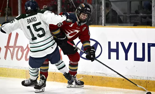 Boston Fleet's Sydney Bard (15) is knocked off her skates as Ottawa Charge's Emily Clark (26) keeps her away from the puck during third-period PWHL hockey game action in Ottawa, Ontario, Saturday, Jan. 11, 2025. (Justin Tang/The Canadian Press via AP)