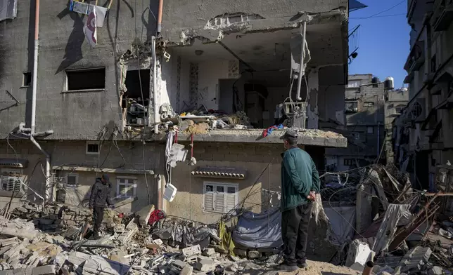 Palestinians look at a damaged residential building following an overnight Israeli strike in Deir al-Balah, Gaza Strip, Wednesday, Jan. 8, 2025. (AP Photo/Abdel Kareem Hana)