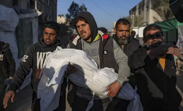 Palestinians carry the body of a relative killed in the Israeli bombardment of the Gaza Strip, at Al-Aqsa Hospital in Deir Al-Balah, Wednesday, Jan. 8, 2025. (AP Photo/Abdel Kareem Hana)