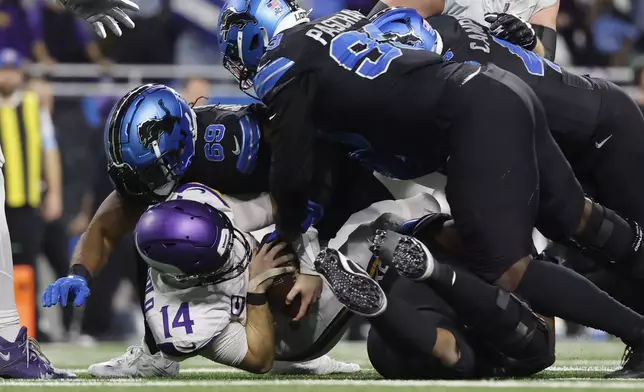 Minnesota Vikings quarterback Sam Darnold (14) is sacked by Detroit Lions linebacker Al-Quadin Muhammad (69) and defensive end Josh Paschal (93) during the second half of an NFL football game Sunday, Jan. 5, 2025, in Detroit. (AP Photo/Rey Del Rio)