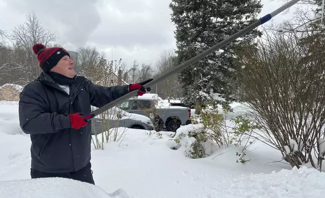 FILE - Resident Todd Brainard cleans snow off of the roof of his home in North Perry, Ohio on Tuesday, Dec. 3, 2024. (AP Photo/Patrick Aftoora-Orsagos, File)