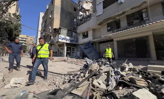 FILE - Municipality workers pass by debris of damaged buildings that were hit by an Israeli airstrike on Tuesday evening in the southern suburbs of Beirut, Lebanon, Wednesday, July 31, 2024. (AP Photo/Hussein Malla, File)