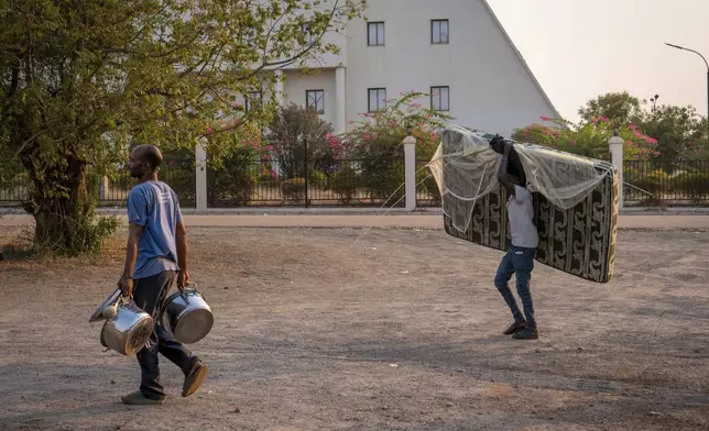 Sudanese nationals carrying their belongings arrive at the South Sudan People's Defense Forces (SSPDF) headquarters after a night of violence in Juba, South Sudan, on Friday, Jan. 17, 2025. (AP Photo/Florence Miettaux)