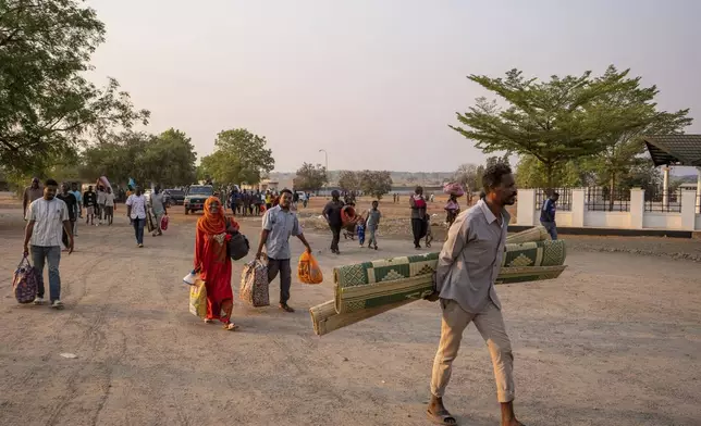 Sudanese nationals carrying their belongings arrive at the South Sudan People's Defense Forces (SSPDF) headquarters after a night of violence in Juba, South Sudan, on Friday, Jan. 17, 2025. (AP Photo/Florence Miettaux)