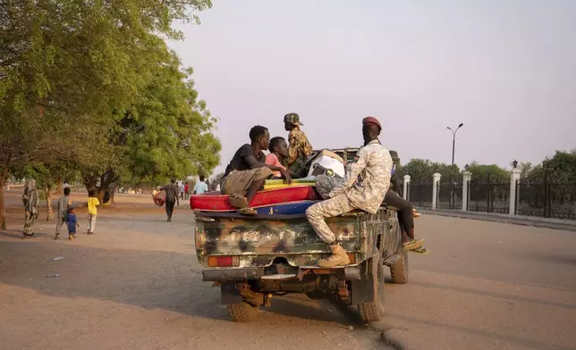 Sudanese nationals carrying their belongings arrive at the South Sudan People's Defense Forces (SSPDF) headquarters after a night of violence in Juba, South Sudan, on Friday, Jan. 17, 2025. (AP Photo/Florence Miettaux)