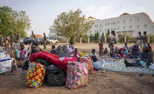Sudanese nationals sit outside the South Sudan People's Defense Forces (SSPDF) headquarters, after a night of violence in Juba, South Sudan, on Friday, Jan. 17, 2025. (AP Photo/Florence Miettaux)