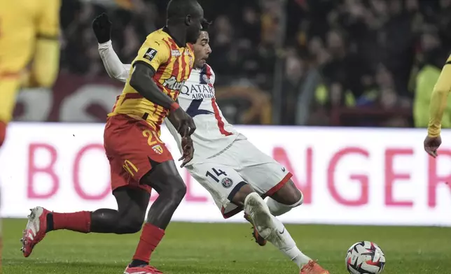 Lens' Malang Sarr, left, and PSG's Desire Doue fight for the ball during the French League One soccer match between Lens and Paris Saint-Germain, at the Bollaert-Delelis stadium in Lens, France, Saturday, Jan. 18, 2025. (AP Photo/Thibault Camus)