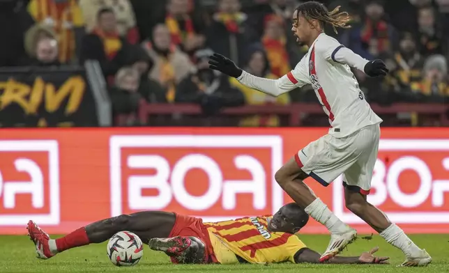 PSG's Bradley Barcola, right, and Lens' Malang Sarr fight for the ball during the French League One soccer match between Lens and Paris Saint-Germain, at the Bollaert-Delelis stadium in Lens, France, Saturday, Jan. 18, 2025. (AP Photo/Thibault Camus)