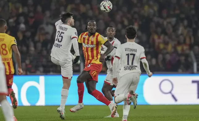 Lens' M'Bala Nzola, controls the ball between PSG's Lucas Beraldo, left, and PSG's Vitinha during the French League One soccer match between Lens and Paris Saint-Germain, at the Bollaert-Delelis stadium in Lens, France, Saturday, Jan. 18, 2025. (AP Photo/Thibault Camus)