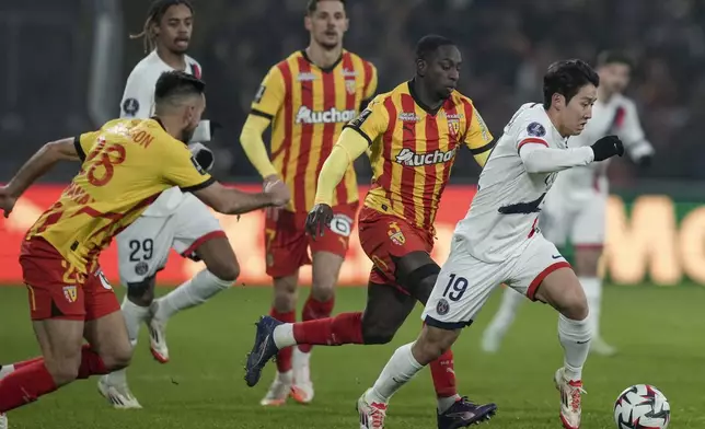 PSG's Lee Kang-in, right, is tackled by Lens players during the French League One soccer match between Lens and Paris Saint-Germain, at the Bollaert-Delelis stadium in Lens, France, Saturday, Jan. 18, 2025. (AP Photo/Thibault Camus)