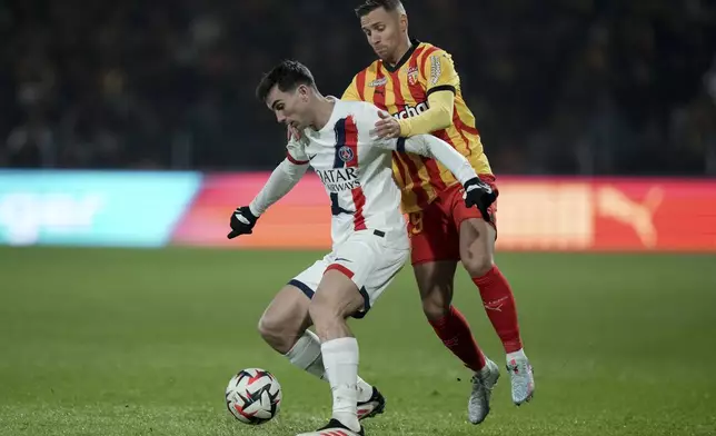 PSG's Fabian Ruiz, left, and Lens' Przemyslaw Frankowski fight for the ball during the French League One soccer match between Lens and Paris Saint-Germain, at the Bollaert-Delelis stadium in Lens, France, Saturday, Jan. 18, 2025. (AP Photo/Thibault Camus)