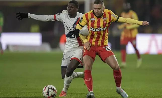 PSG's Nuno Mendes, left, and Lens' Przemyslaw Frankowski fight for the ball during the French League One soccer match between Lens and Paris Saint-Germain, at the Bollaert-Delelis stadium in Lens, France, Saturday, Jan. 18, 2025. (AP Photo/Thibault Camus)
