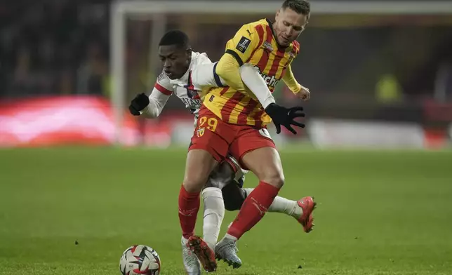 PSG's Nuno Mendes, left, and Lens' Przemyslaw Frankowski fight for the ball during the French League One soccer match between Lens and Paris Saint-Germain, at the Bollaert-Delelis stadium in Lens, France, Saturday, Jan. 18, 2025. (AP Photo/Thibault Camus)