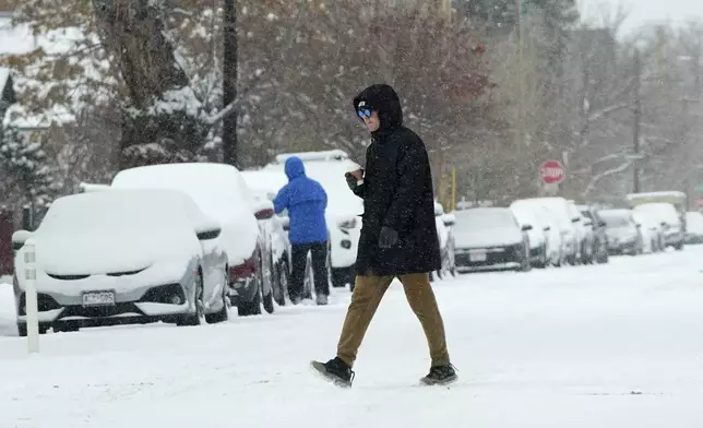 A pedestrian crosses First Avenue as a winter storm sweeps over the intermountain West, plunging temperatures into the single digits and bringing along a light snow in its wake Saturday, Jan. 18, 2025, in Denver. (AP Photo/David Zalubowski)