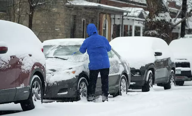 A motorist clears ice and snow from the windshield of a vehicle as a winter storm sweeps over the intermountain West, plunging temperatures into the single digits and bringing along a light snow in its wake Saturday, Jan. 18, 2025, in Denver. (AP Photo/David Zalubowski)
