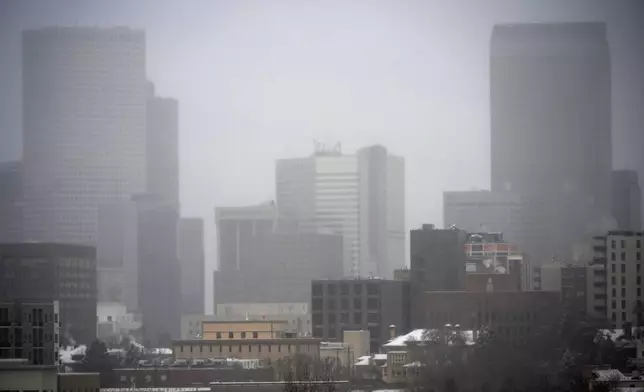 A light snow shrouds the skyline as a winter storm sweeps over the intermountain West, plunging temperatures into the single digits and bringing along a light snow in its wake Saturday, Jan. 18, 2025, in Denver. (AP Photo/David Zalubowski)