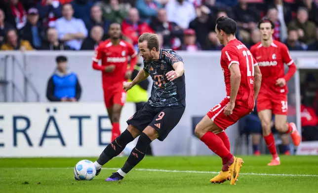 Munich's Harry Kane, left, scores during the Bundesliga soccer match between SC Freiburg and Bayern Munich at Europa-Park Stadium, Freiburg, Germany, Saturday Jan. 25, 2025. (Tom Weller/dpa via AP)