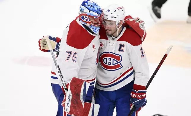 Montreal Canadiens goaltender Jakub Dobes (75) and center Nick Suzuki (14) celebrate after an NHL hockey game against the Washington Capitals, Friday, Jan. 10, 2025, in Washington. (AP Photo/Nick Wass)