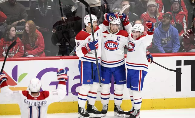 Montreal Canadiens center Nick Suzuki, second from right, celebrates after his winning goal during overtime with defenseman Mike Matheson (8), right wing Cole Caufield, right, and right wing Brendan Gallagher (11) in an NHL hockey game against the Washington Capitals, Friday, Jan. 10, 2025, in Washington. (AP Photo/Nick Wass)