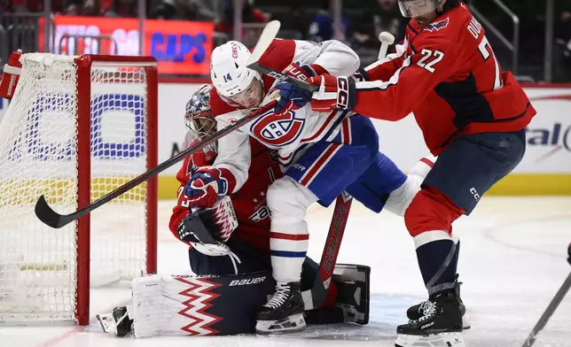 Montreal Canadiens center Nick Suzuki (14) collides with Washington Capitals goaltender Charlie Lindgren, left, as he battles with Capitals right wing Brandon Duhaime (22) during the second period of an NHL hockey game, Friday, Jan. 10, 2025, in Washington. (AP Photo/Nick Wass)