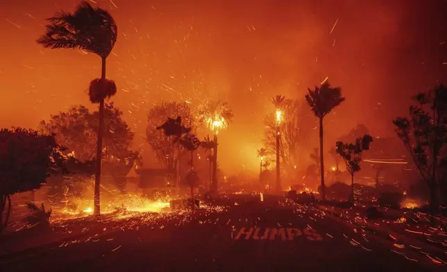 The Palisades Fire ravages a neighborhood amid high winds in the Pacific Palisades neighborhood of Los Angeles, Tuesday, Jan. 7, 2025. (AP Photo/Ethan Swope)