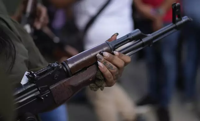 A member of a government-backed militia holds a weapon before a march in Caracas, Venezuela, Tuesday, Jan. 7, 2025, days ahead of President Nicolás Maduro's inauguration for a third term. (AP Photo/Matias Delacroix)