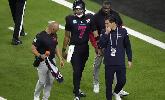 Houston Texans quarterback C.J. Stroud (7) is helped off the field after getting injured during the first half of an NFL football game against the Baltimore Ravens, Wednesday, Dec. 25, 2024, in Houston. (AP Photo/Eric Christian Smith)