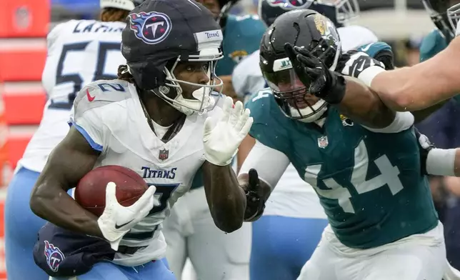 Tennessee Titans running back Tyjae Spears, left, runs the ball past Jacksonville Jaguars defensive end Travon Walker (44) during the first half of an NFL football game, Sunday, Dec. 29, 2024, in Jacksonville, Fla. (AP Photo/John Raoux)