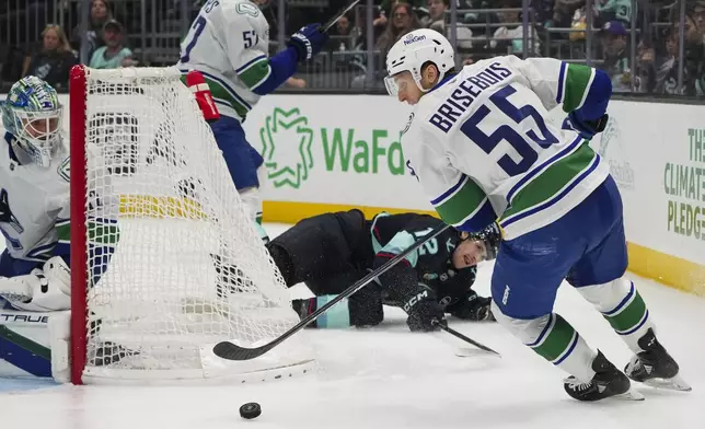 Vancouver Canucks defenseman Guillaume Brisebois (55) clears the puck against Seattle Kraken left wing Tye Kartye, back center, during the second period of an NHL hockey game Thursday, Jan. 2, 2025, in Seattle. (AP Photo/Lindsey Wasson)