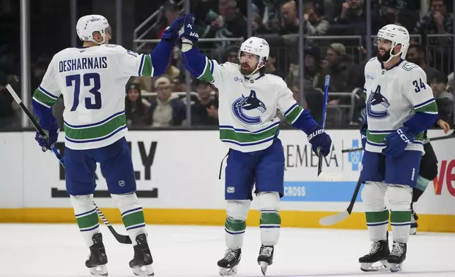 Vancouver Canucks right wing Conor Garland, center, celebrates his goal against the Seattle Kraken with teammates Vincent Desharnais, left, and Phillip Di Giuseppe, right, during the second period of an NHL hockey game Thursday, Jan. 2, 2025, in Seattle. (AP Photo/Lindsey Wasson)