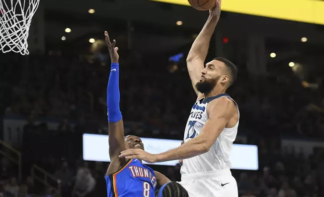 Minnesota Timberwolves center Rudy Gobert, right, dunks over Oklahoma City Thunder forward Jalen Williams, left, during the second half of an NBA basketball game, Tuesday, Dec. 31, 2024, in Oklahoma City. (AP Photo/Kyle Phillips)