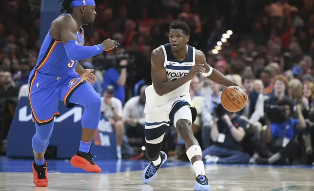 Minnesota Timberwolves guard Anthony Edwards, right, drives past Oklahoma City Thunder guard Luguentz Dort, left, during the second half of an NBA basketball game, Tuesday, Dec. 31, 2024, in Oklahoma City. (AP Photo/Kyle Phillips)